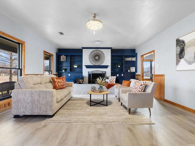 living area with wood finished floors, built in features, and a healthy amount of sunlight