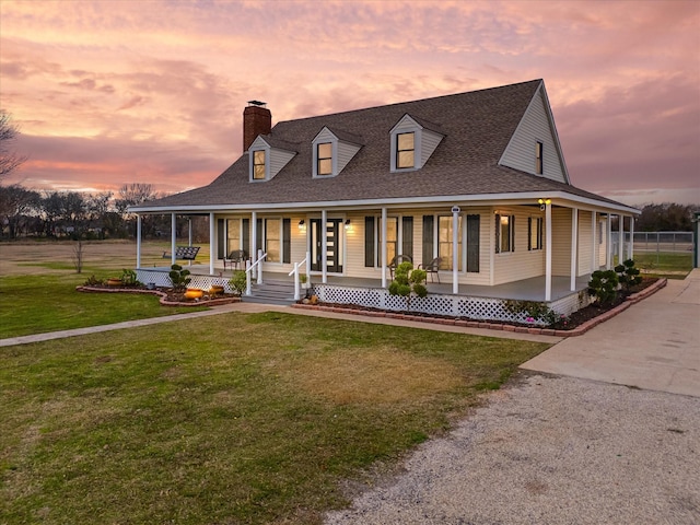 country-style home featuring a chimney, a front lawn, a porch, and roof with shingles