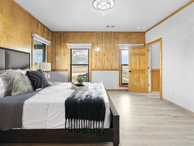 bedroom featuring ornamental molding, light hardwood / wood-style floors, and wood walls