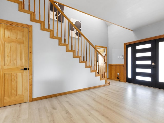 entrance foyer featuring baseboards, wainscoting, stairway, wood finished floors, and wood walls