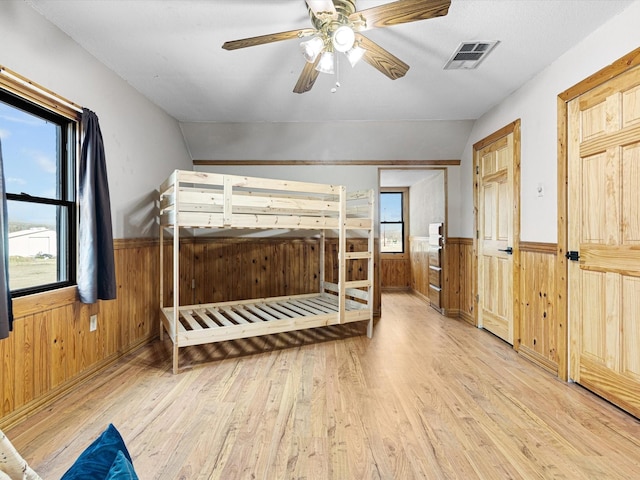 unfurnished bedroom featuring ceiling fan, wooden walls, and light hardwood / wood-style flooring