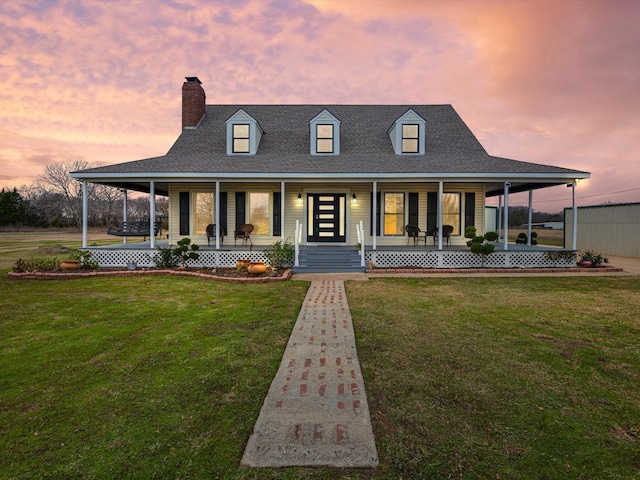 view of front of house featuring a porch, a chimney, a front yard, and a shingled roof