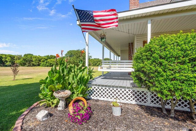 view of exterior entry featuring a yard and covered porch