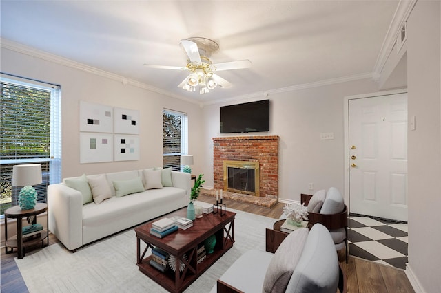 living room featuring ceiling fan, light wood-type flooring, crown molding, and a brick fireplace