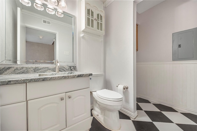 bathroom with electric panel, vanity, ornamental molding, and toilet