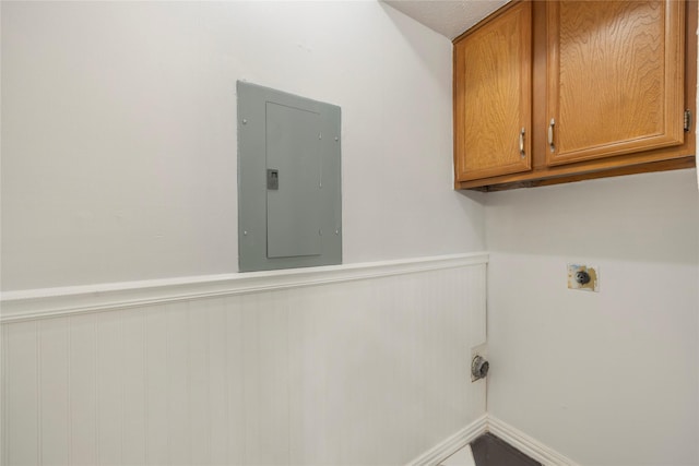 clothes washing area featuring electric dryer hookup, electric panel, and cabinets