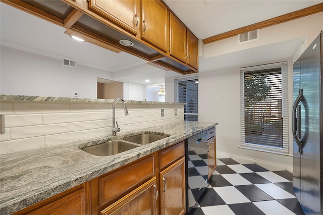 kitchen featuring sink, dishwasher, light stone counters, backsplash, and stainless steel fridge