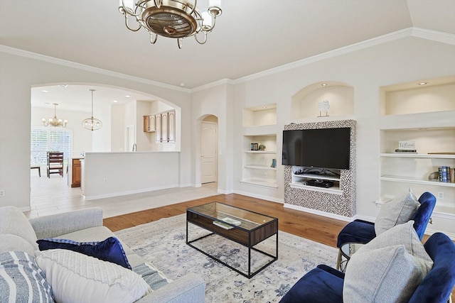 living room featuring ornamental molding, built in features, a chandelier, and light wood-type flooring