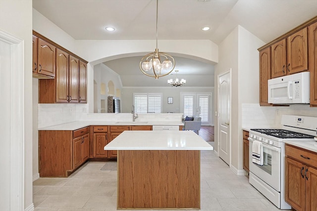 kitchen featuring pendant lighting, white appliances, backsplash, sink, and a chandelier