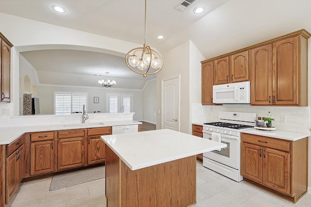 kitchen featuring sink, a notable chandelier, lofted ceiling, decorative light fixtures, and white appliances