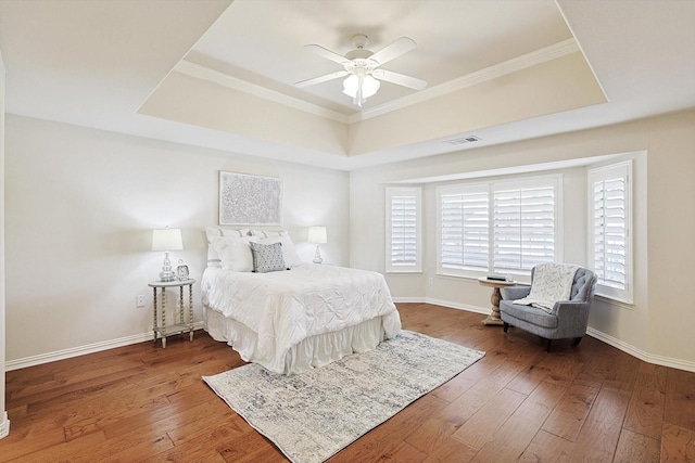 bedroom featuring hardwood / wood-style floors, ceiling fan, a raised ceiling, and ornamental molding