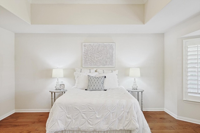 bedroom with hardwood / wood-style floors and a raised ceiling