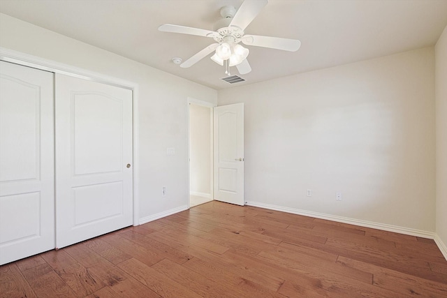 unfurnished bedroom featuring a closet, hardwood / wood-style flooring, and ceiling fan