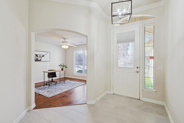 entrance foyer with light tile patterned floors, ceiling fan with notable chandelier, ornamental molding, and a healthy amount of sunlight