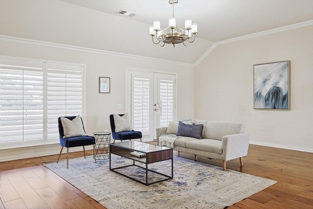 living room with a chandelier, hardwood / wood-style floors, vaulted ceiling, and crown molding