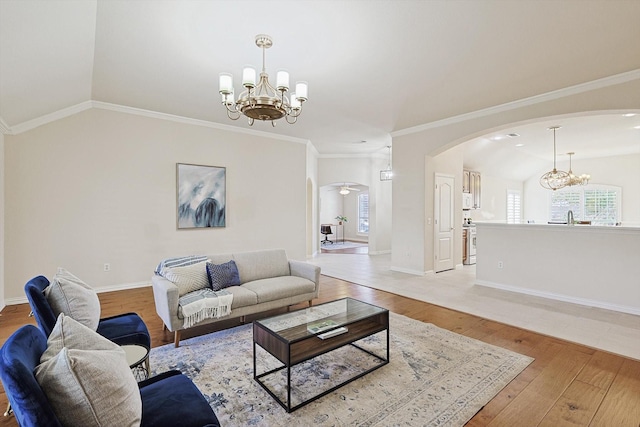 living room featuring vaulted ceiling, crown molding, and a chandelier