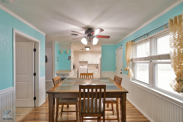 dining space with wood-type flooring, washer / clothes dryer, ceiling fan, and crown molding