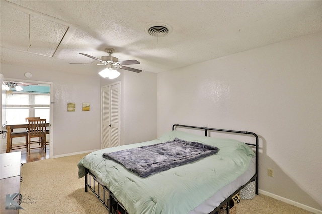 bedroom featuring ceiling fan, light colored carpet, a textured ceiling, and a closet