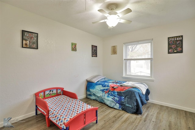 bedroom with ceiling fan, wood-type flooring, and a textured ceiling