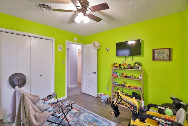 game room featuring ceiling fan, a textured ceiling, and hardwood / wood-style flooring