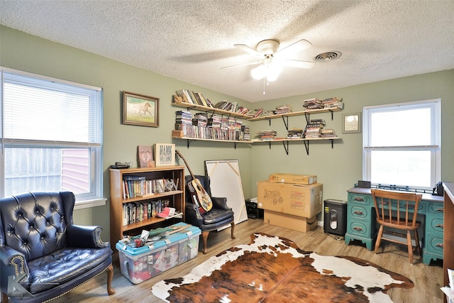 office area with a textured ceiling, light hardwood / wood-style flooring, plenty of natural light, and ceiling fan