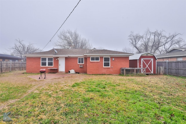 rear view of property featuring a lawn, a patio, and a shed