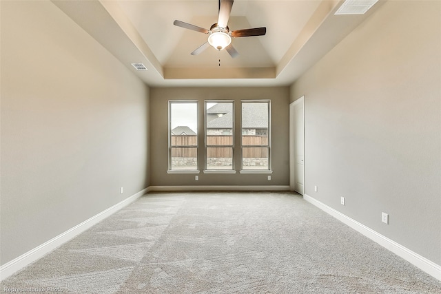 unfurnished room with light carpet, a tray ceiling, and ceiling fan