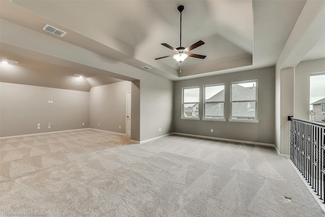 unfurnished room with light carpet, a tray ceiling, and ceiling fan