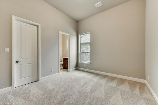 unfurnished bedroom with ensuite bathroom and light colored carpet