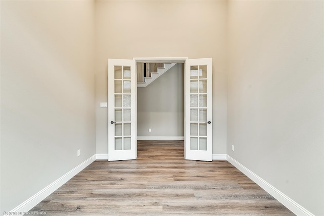 unfurnished room with french doors, a towering ceiling, and light hardwood / wood-style floors