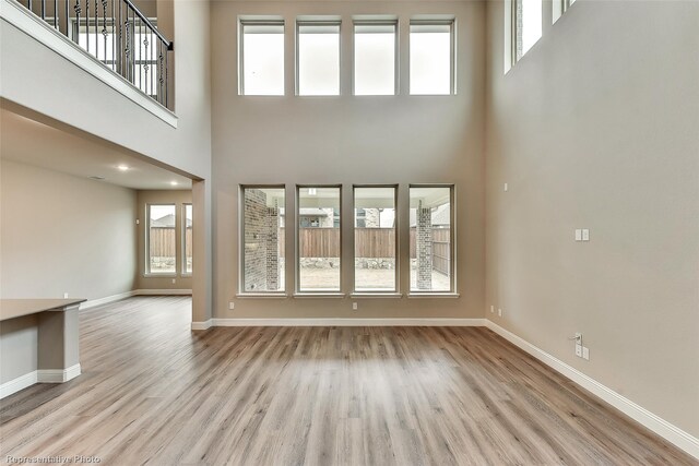 unfurnished living room featuring light hardwood / wood-style floors and a towering ceiling