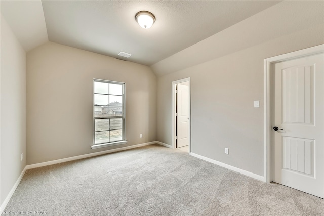 unfurnished room featuring light colored carpet and lofted ceiling