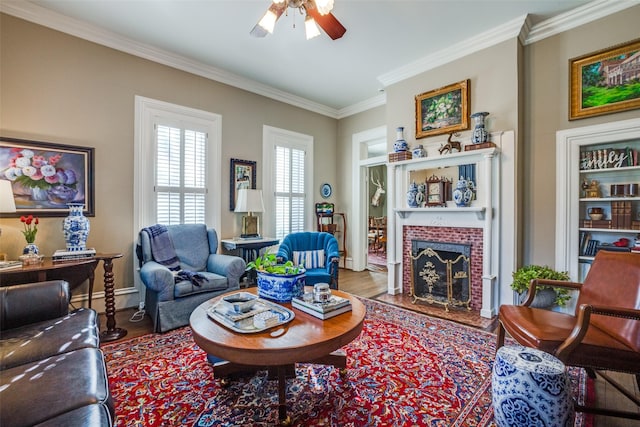 living room with ceiling fan, wood-type flooring, ornamental molding, and a brick fireplace