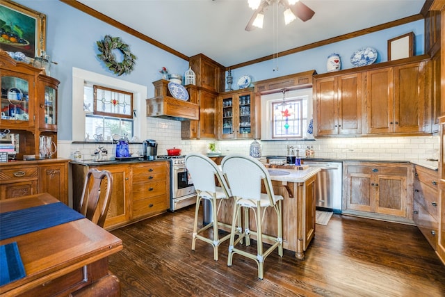 kitchen with appliances with stainless steel finishes, tasteful backsplash, ornamental molding, a center island, and dark hardwood / wood-style floors