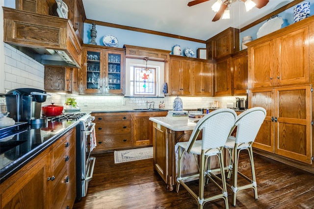 kitchen featuring high end range, tasteful backsplash, crown molding, pendant lighting, and dark hardwood / wood-style floors