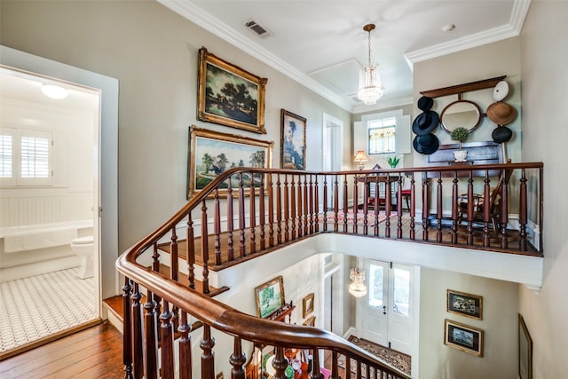 stairs featuring hardwood / wood-style flooring, crown molding, and a notable chandelier