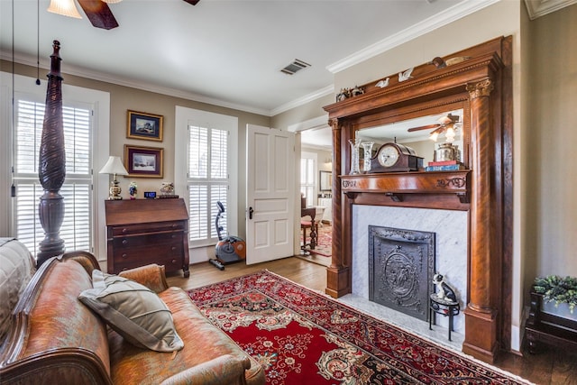 living room with ceiling fan, ornamental molding, a healthy amount of sunlight, and light hardwood / wood-style floors