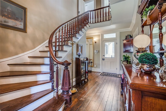 foyer featuring crown molding, a towering ceiling, and dark wood-type flooring