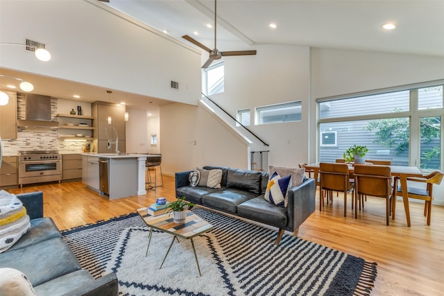 living room with light hardwood / wood-style floors, high vaulted ceiling, and ceiling fan