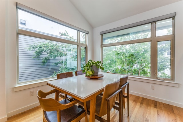 dining space featuring light wood-type flooring and vaulted ceiling