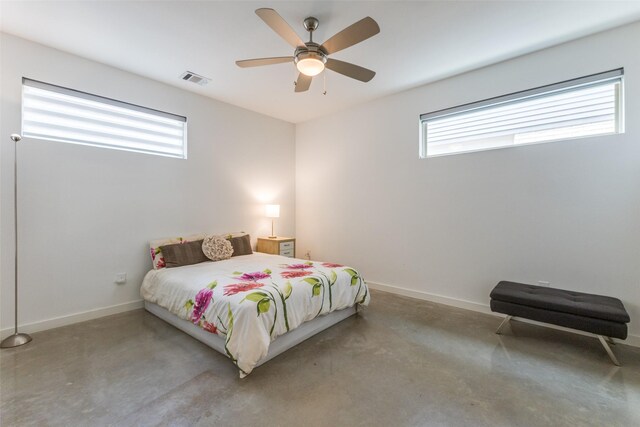 bedroom with ceiling fan, concrete flooring, and multiple windows