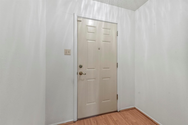 doorway featuring light hardwood / wood-style floors and a textured ceiling