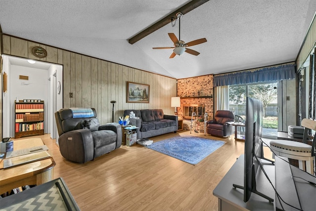 living room featuring wood walls, light hardwood / wood-style flooring, vaulted ceiling with beams, ceiling fan, and a textured ceiling