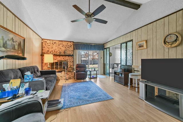 living room featuring a textured ceiling, lofted ceiling with beams, ceiling fan, and wood walls