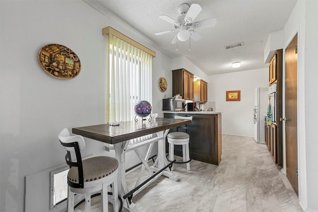 kitchen with kitchen peninsula, ceiling fan, a textured ceiling, and white refrigerator