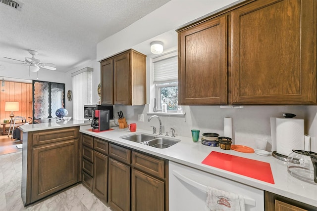 kitchen with dishwasher, sink, ceiling fan, a textured ceiling, and kitchen peninsula