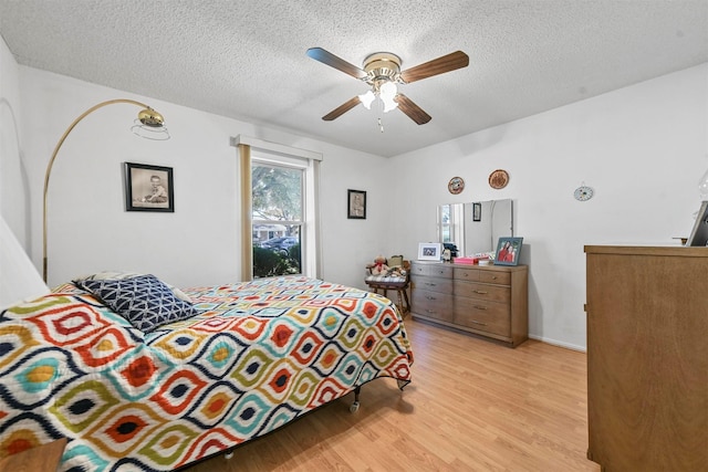 bedroom with a textured ceiling, light hardwood / wood-style floors, and ceiling fan