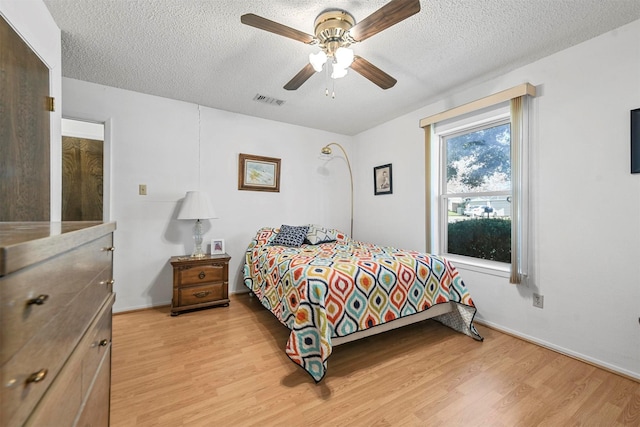 bedroom with ceiling fan, light hardwood / wood-style flooring, and a textured ceiling