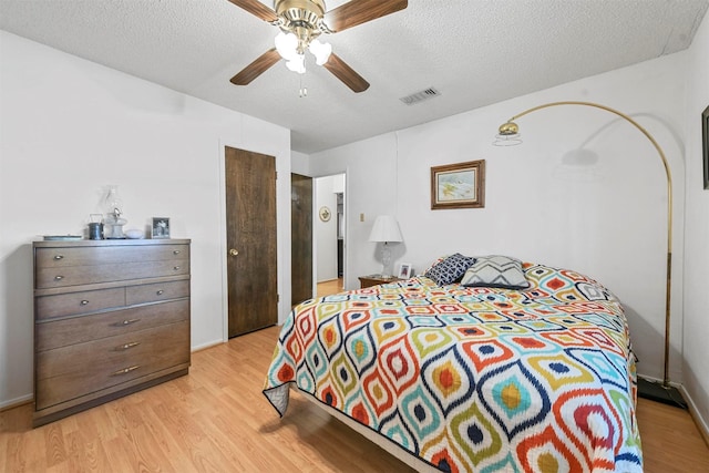 bedroom featuring ceiling fan, a textured ceiling, and light hardwood / wood-style flooring