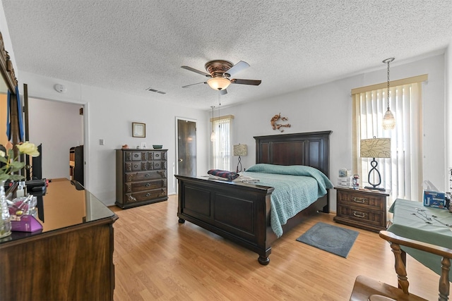 bedroom featuring ceiling fan, light wood-type flooring, and a textured ceiling